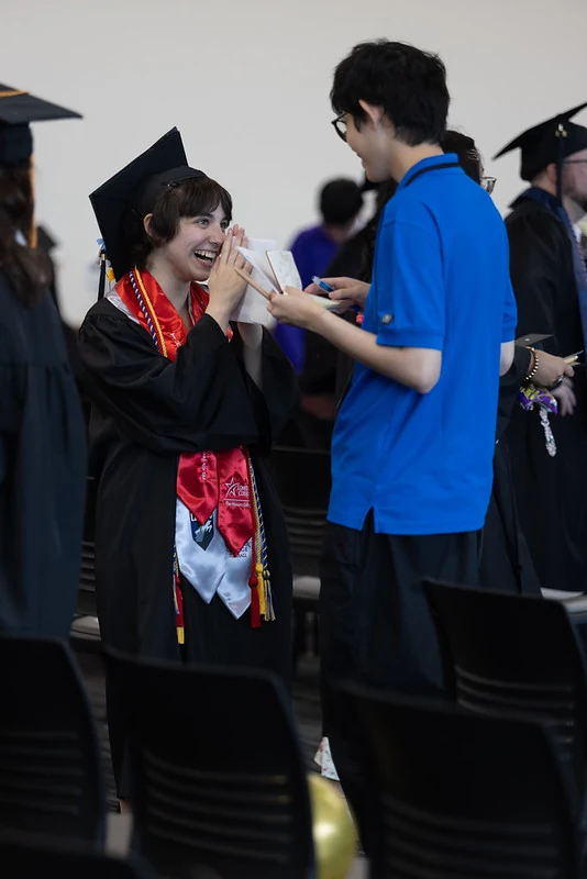 Dongfang in a blue polo interacting with a smiling graduate